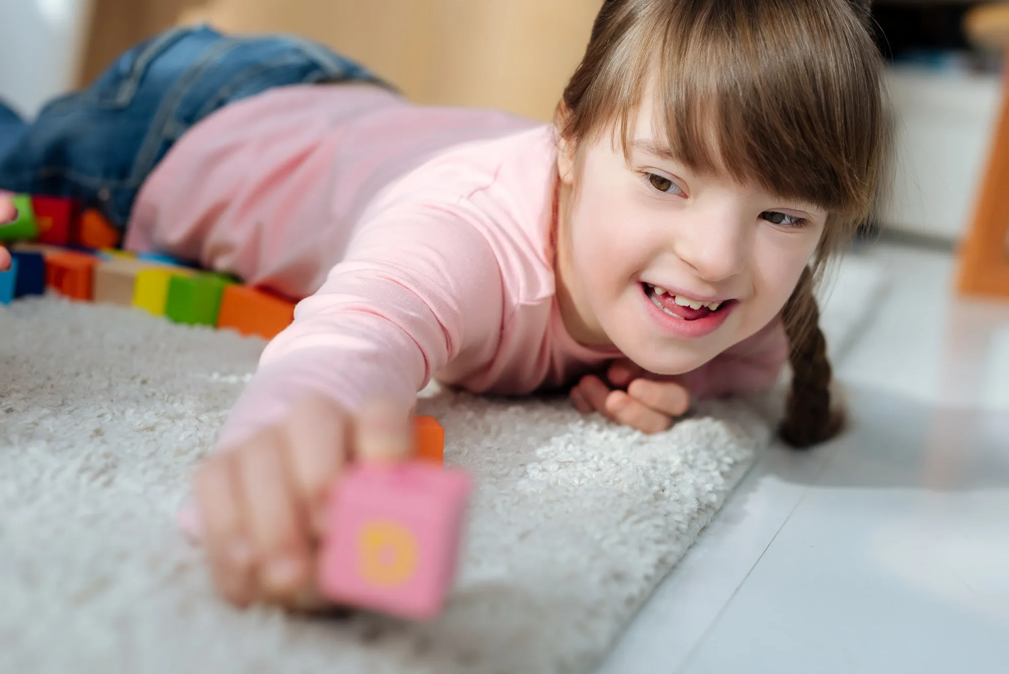 Child with down syndrome holding toy cube